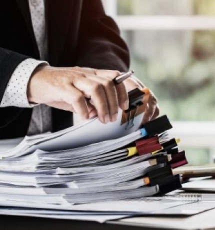 Person browsing through a stack of documents and reports, likely related to acoustic insulation projects aimed at improving sound comfort in various environments.